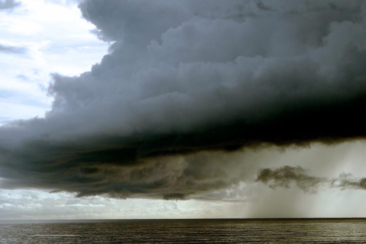 Large, dark cloud looms over the sea.