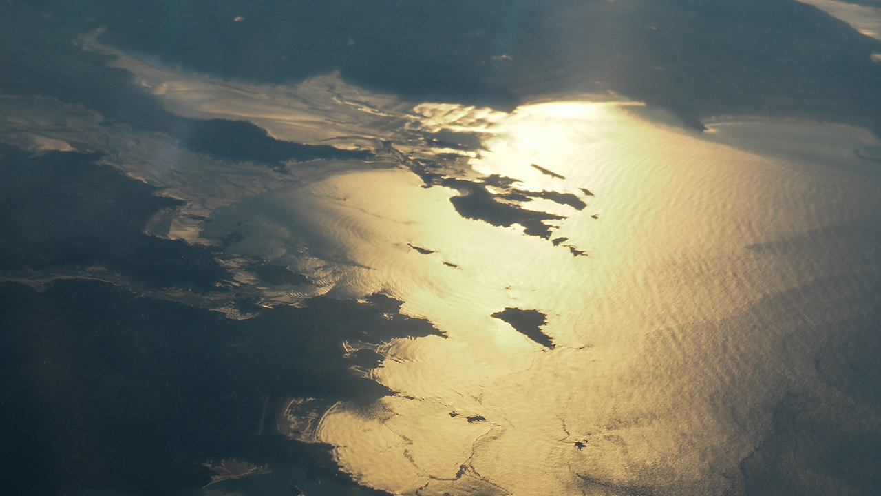 Golden sunlight reflecting on dark blue and grey ocean